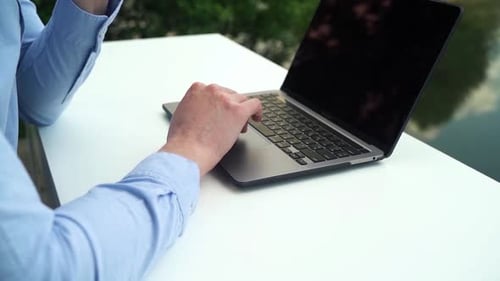 A man works at an office desk in nature near a river