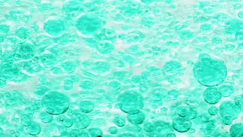 macro shot of blue bubbles in water floating right with yellow background