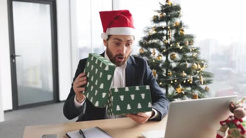 Happy Businessman Opens Christmas Gift in Office
