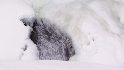 Schmelzwasserstrom, der im Winter durch Schnee und Eis fließt