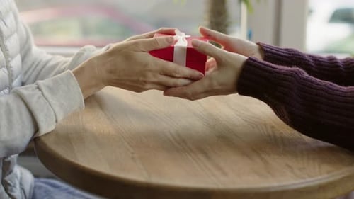 Close Up of Hands Exchanging a Red Gift