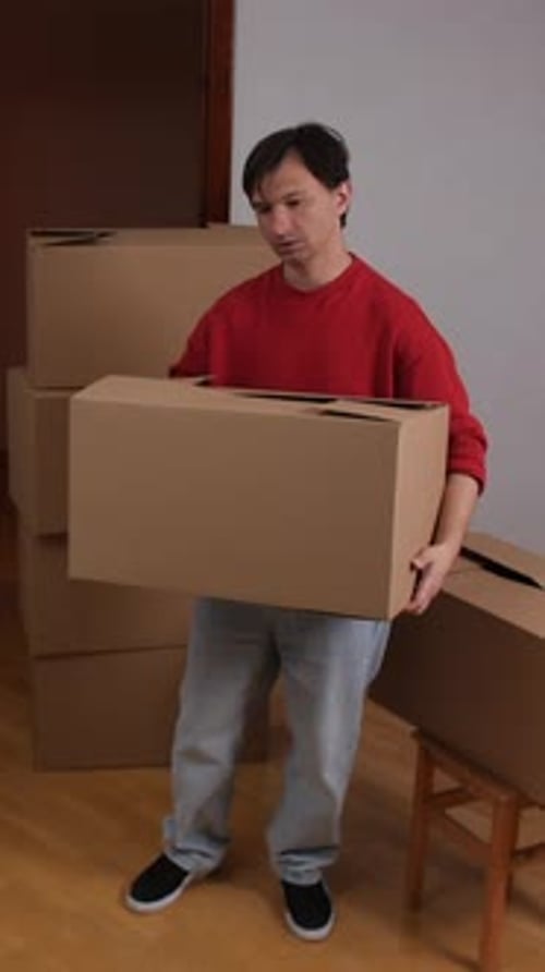 Young Adult Man Carries Cardboard Box Indoors