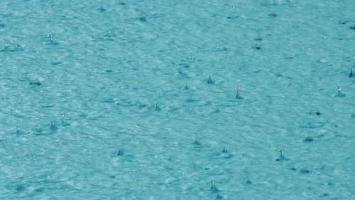 Sommerregen plätschert auf einem Hintergrund der Aquawasseroberfläche