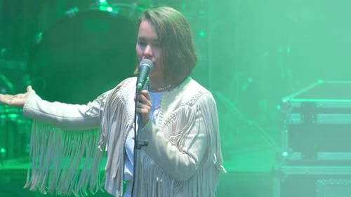 Woman Singing Into Microphone on Stage in Concert