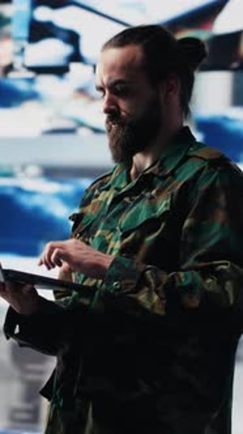 Man Typing on Laptop in Front of Screens