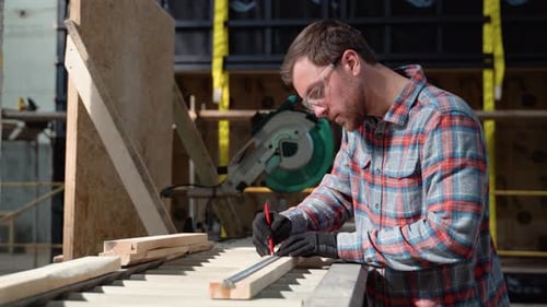 Building Contractor Worker Using Hand Held Worm Drive Circular Saw to Cut Boards on a New Home