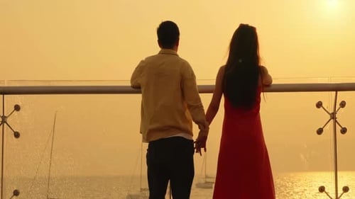 Young romantic couple watching sunset silhouette at the beach enjoying travel vacation summer