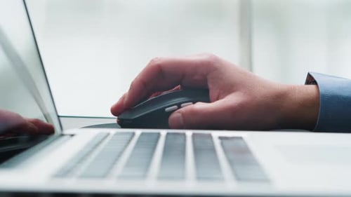 Closeup of a Man's Hand Working at a Laptop Using a Wireless Mouse