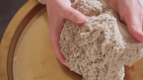 Hands Molding Kinetic Sand on Golden Tray Close-up