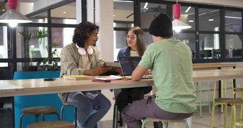 Divers collègues invités par une tablette, discutant du projet tout en faisant référence à un ordinateur portable à une table haute