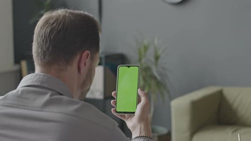 Man Looking at Smartphone with Green Screen in Office