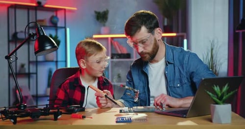 Boy and Man Soldering Technology Together