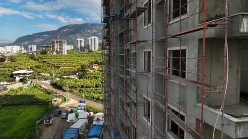 Los constructores trabajan de frente al edificio, se apoyan en el andamio