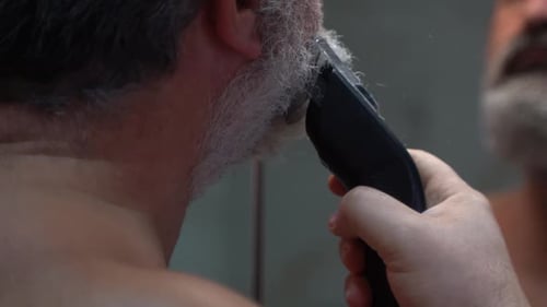 Man Trims Gray Beard With Electric Razor