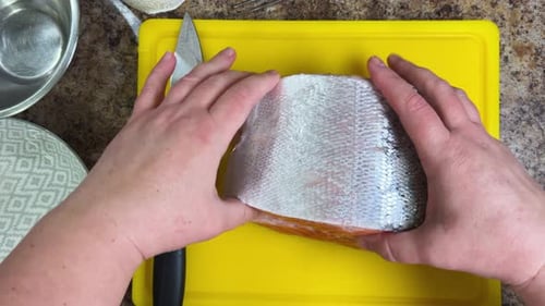 Cutting salmon fish with a knife for further cooking, preparing the fillet and removing the bones.