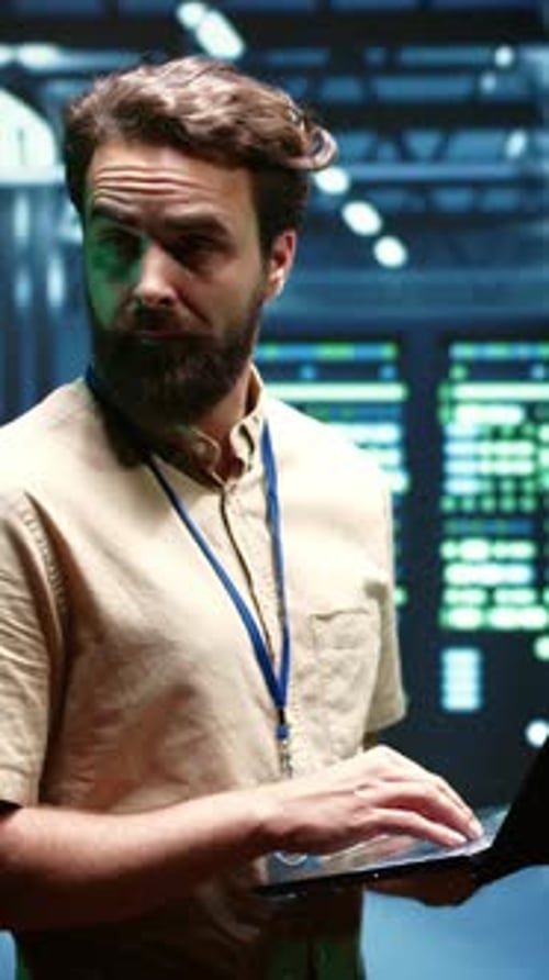 Man Working on Laptop in Dark Server Room