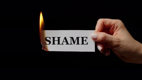 Female Hand Holding Burning Sheet with Note Shame in Studio