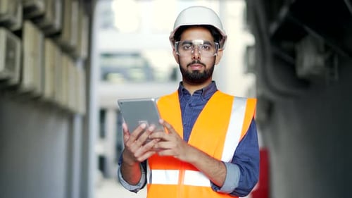 Smiling Engineer Using Tablet in Industrial Setting