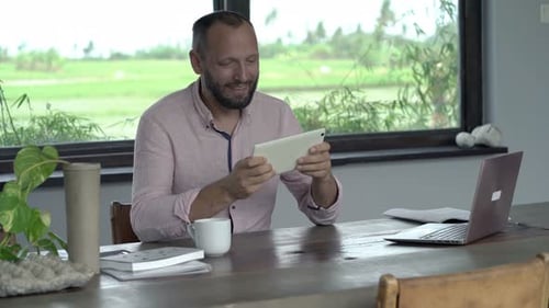 Man Using Tablet at Wooden Table Indoors