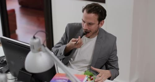 Adult male having lunch whilst working at desk in office