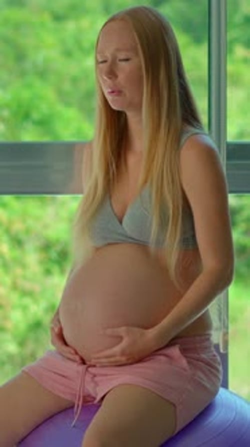 Pregnant Woman Sits on Exercise Ball Indoors