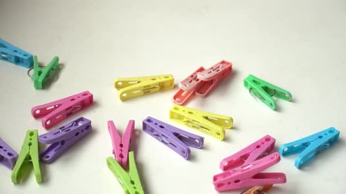 Many colored used clothespins falling down on a table