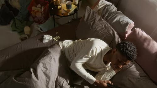 Man Relaxing in Bed Using Smartphone