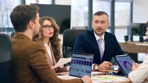 Business meeting in an office, workers discussing business affairs. Gadgets and papers with charts o