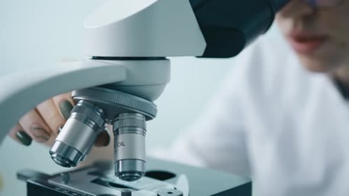 Lab Technician Adjusting Modern Microscope in a Lab