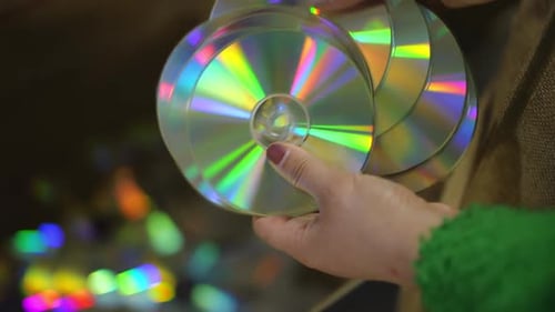Closeup High Angle View Female Hands Throwing Compact Discs in Box Indoors in Slow Motion Closeup