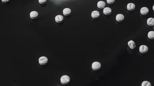 White Pills on Black Surface Close Up
