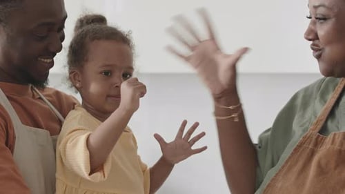 Petite fille donnant des coups de poing à une mère joyeuse dans la cuisine
