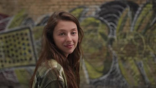 Smiling Woman Posing in Front of Graffiti Wall