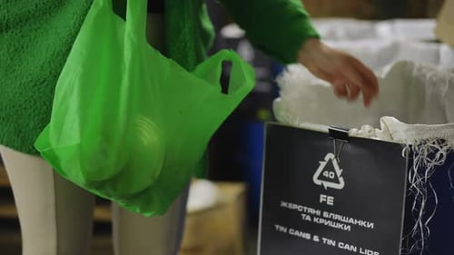Mujer joven irreconocible que coloca latas de una bolsa de plástico en una caja en cámara lenta, mujer caucásica