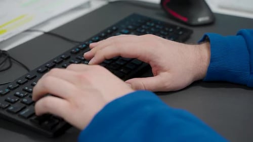 Man typing on a keyboard in an office.