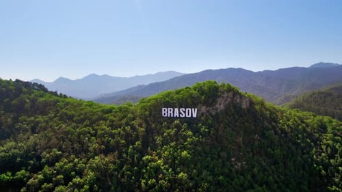 Brasov sign on the top of the hill near the city, green trees, Romania