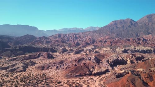 Aerial view drone flying over scenic red rocky mountains landscape with a clear blue sky.