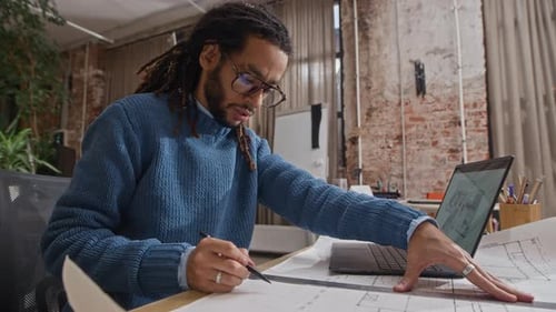 Man Working on Architectural Plans in Creative Workplace
