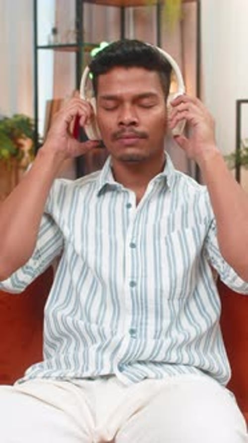 Man Enjoys Music with Headphones and Smartphone Indoors