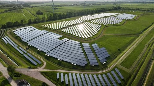 Aerial footage of photovoltaic power plant and wind turbine farm situated by landfill.