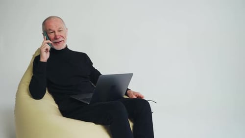 Senior Man Talking on Phone with Laptop