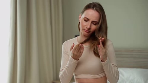 Woman Inspects Damaged Hair in Bedroom