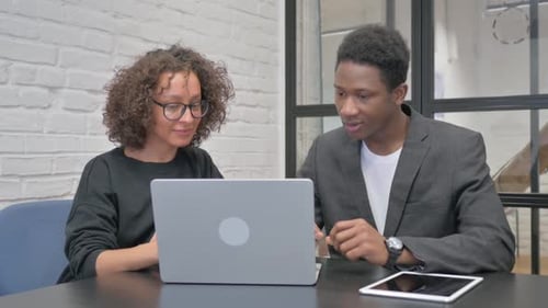 Young Adults Collaborating on Laptop in Modern Office