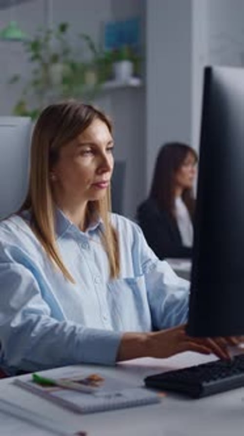 Focused Office Worker Typing on Desktop Computer While Concentrating on Task in Modern Workspace