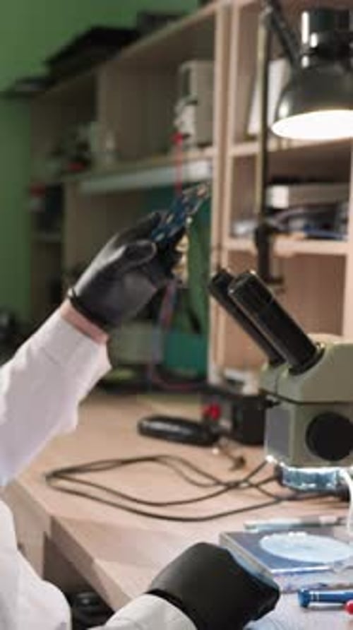 Technician Inspecting Computer Chip Under Microscope
