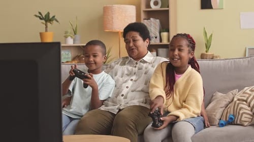 Mature Adult Gaming with Two Children on Couch