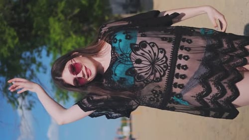 Beautiful, attractive, happy girl posing on a sandy beach on a sunny day in a blue swimsuit, sunglas