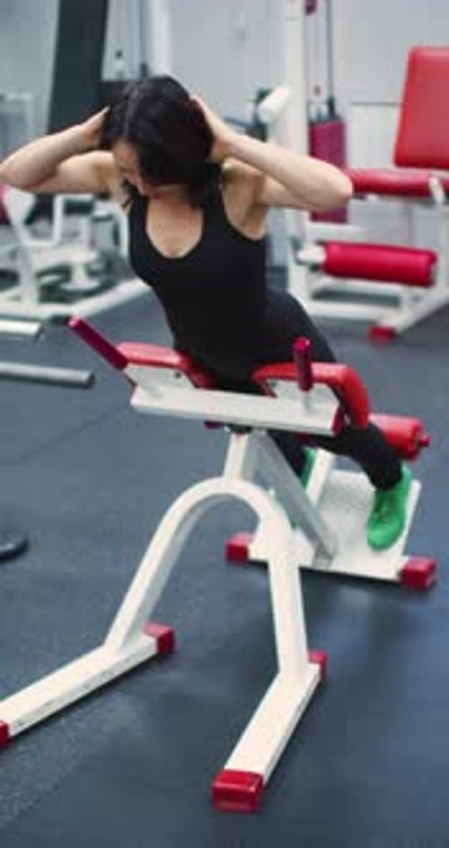 Woman in Her 40s Does Back Extensions Focusing on Core and Back Strength in the Gym