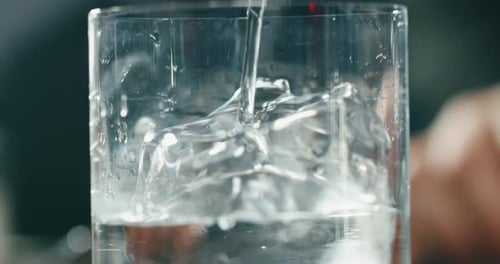 Water is Poured Into Glass of Ice