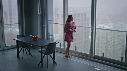 Woman in Robe Looks at City View